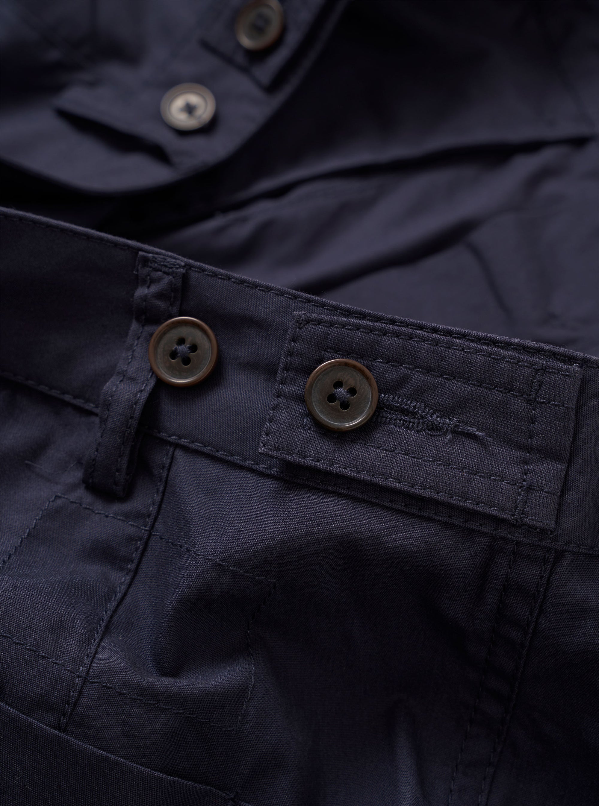 The Navy Peached Poplin Dutch Pant is shown from the rear in a flat lay against a white background. The image highlights the loose, wide-leg fit and features two large rear patch pockets with button closures.