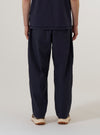 A model wears the Navy Peached Poplin Dutch Pant, shown from the waist down from a rear three-quarter angle against a plain white background. The image highlights the exceptionally wide leg, the soft matte texture of the navy peached poplin fabric, and a rear patch pocket. The model is also wearing dark shoes.