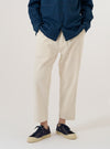 A model wears the Ecru Slub Drill Hi Water Trouser against a plain, neutral background. The trousers feature a slim, cropped fit and a drawstring waistband. The ecru-colored cotton fabric has a visible slub drill texture. The model is shown from the waist down, highlighting the garment's length and structured design.