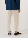 A model wears the Ecru Slub Drill Hi Water Trouser, shown from a rear three-quarter angle against a plain white background. The trousers feature a relaxed, cropped fit that finishes above the ankle, a drawstring waistband, and a single rear patch pocket. The off-white cotton slub drill fabric has a visible textured grain.