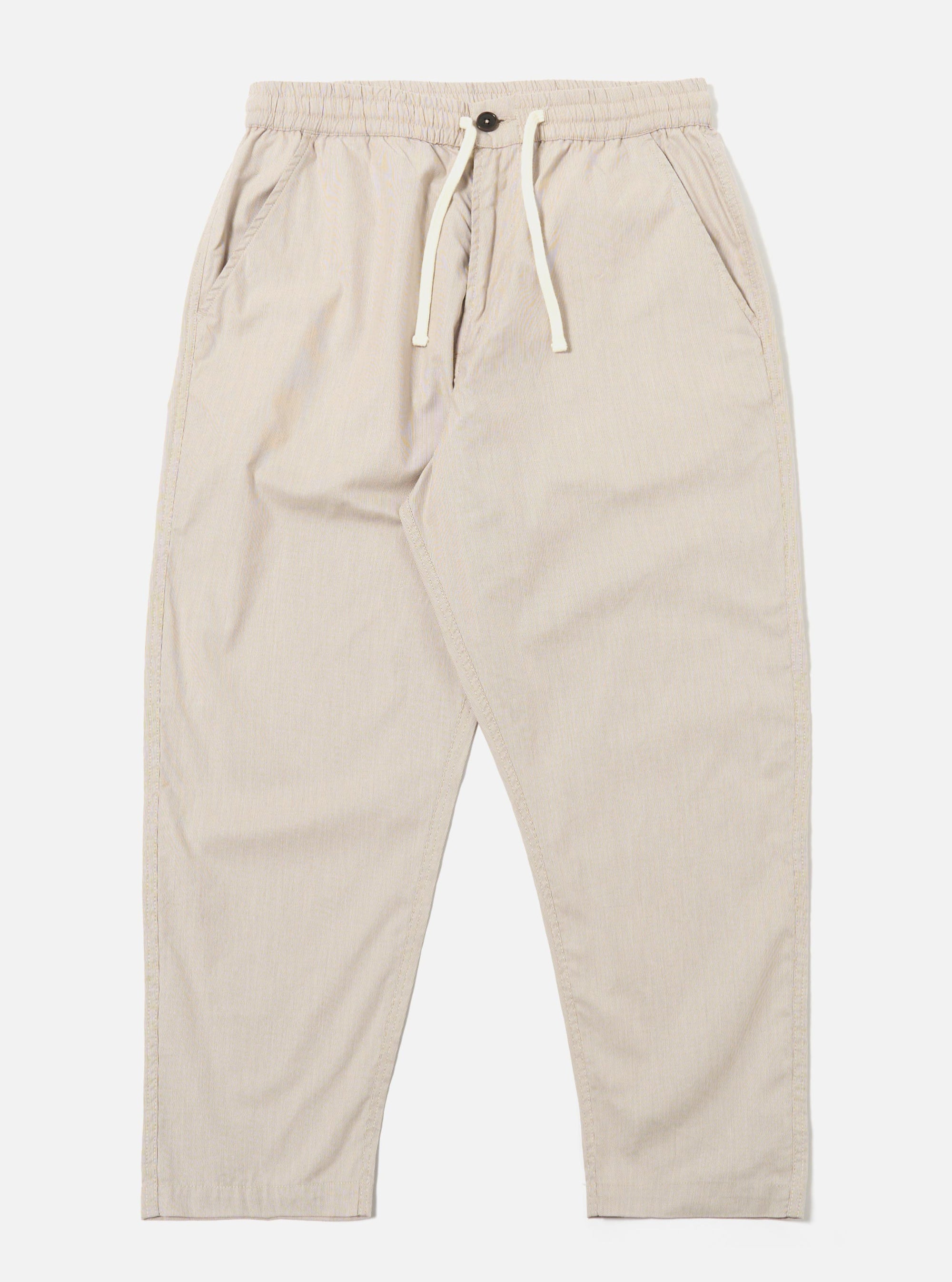 The Brown Kennedy Stripe Hi Water Trouser is shown as a flat lay against a white background. The trousers feature a vertical striped pattern in brown and tan tones. They are designed with an elasticated waistband, a visible drawstring, and a slim, cropped leg.
