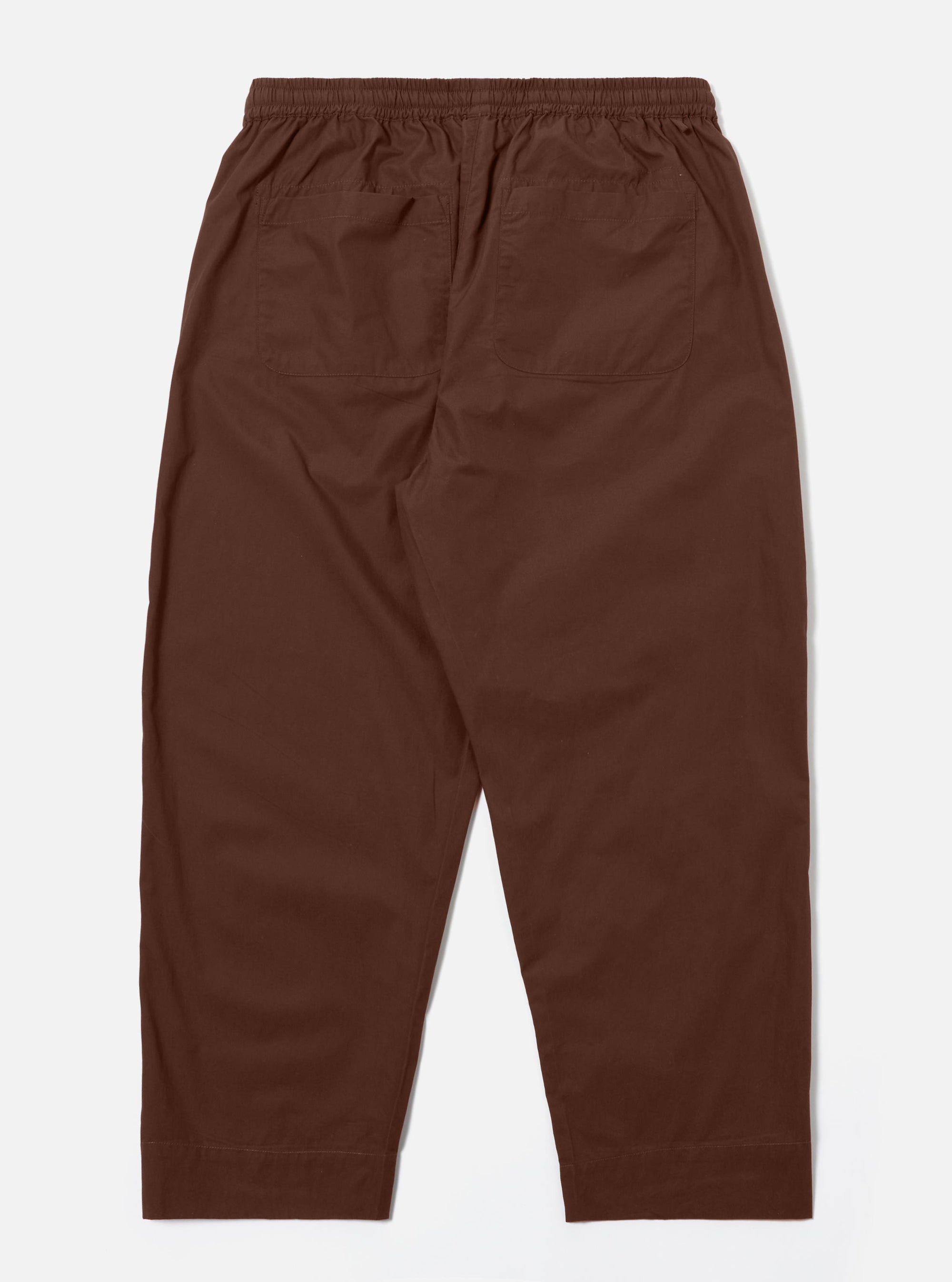 The Brown Peached Poplin Judo Pant is shown from the rear as a flat lay against a plain white background. The image highlights the elasticated waistband and the two large rear patch pockets. The smooth texture of the brown cotton poplin fabric is visible.