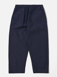 The Navy Peached Poplin Judo Pant is shown as a flat lay against a white background. The trousers feature a relaxed, wide-leg fit with a distinctive wrap-front waist, an integrated drawstring, and a single large patch pocket on the right leg. The fabric has a smooth, matte finish characteristic of peached poplin.
