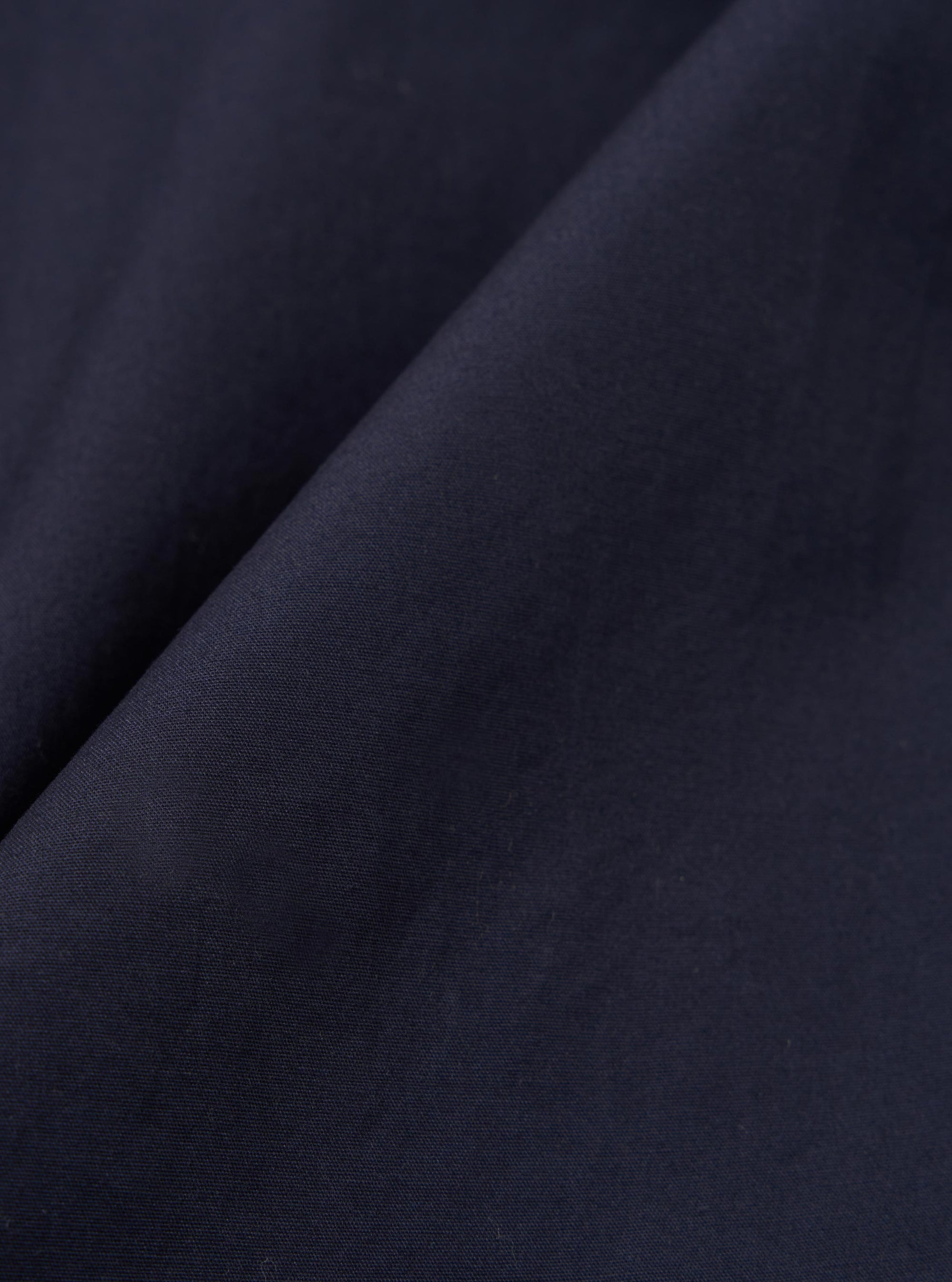 A close-up swatch image of the Navy Peached Poplin Judo Pant fabric displays a deep navy blue color with a smooth, matte finish. The fine, dense weave of the cotton poplin material is clearly visible, highlighting the peached texture.