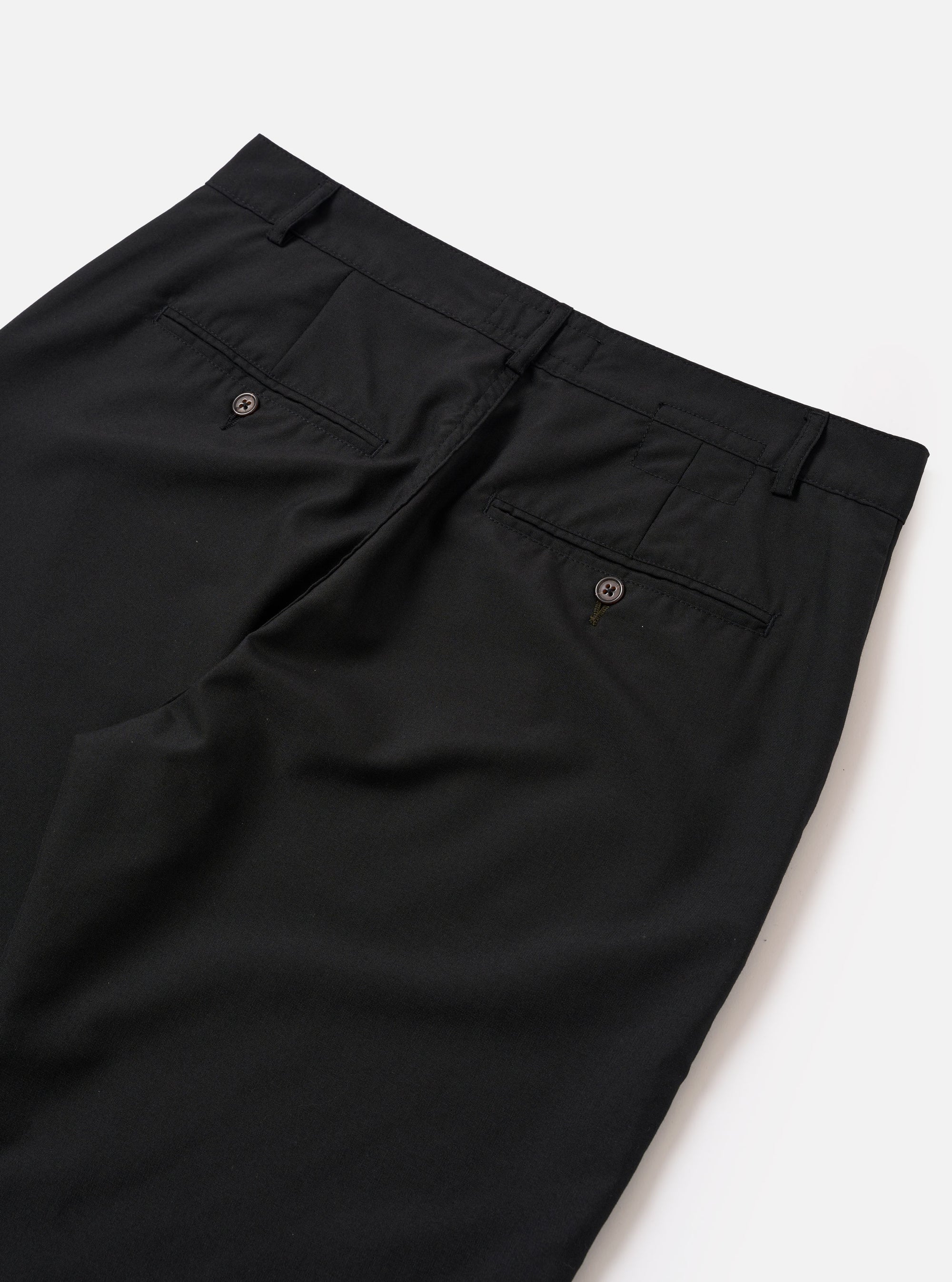 The Black Tropical Suiting Military Chino is shown from a rear angle as a flat lay against a plain white background. The image highlights the two rear jetted buttoned pockets and the clean, tapered cut of the black tropical suiting fabric through the legs to the hem.