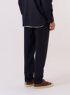 A model is wearing the Navy Tropical Suiting Military Chino, shown from a rear three-quarter angle against a plain white background. The trousers feature a straight-leg fit and are made from a smooth, navy blue tropical suiting fabric. The image highlights the construction of the rear, including a single button-down flap pocket on the right side and a clean waistband.
