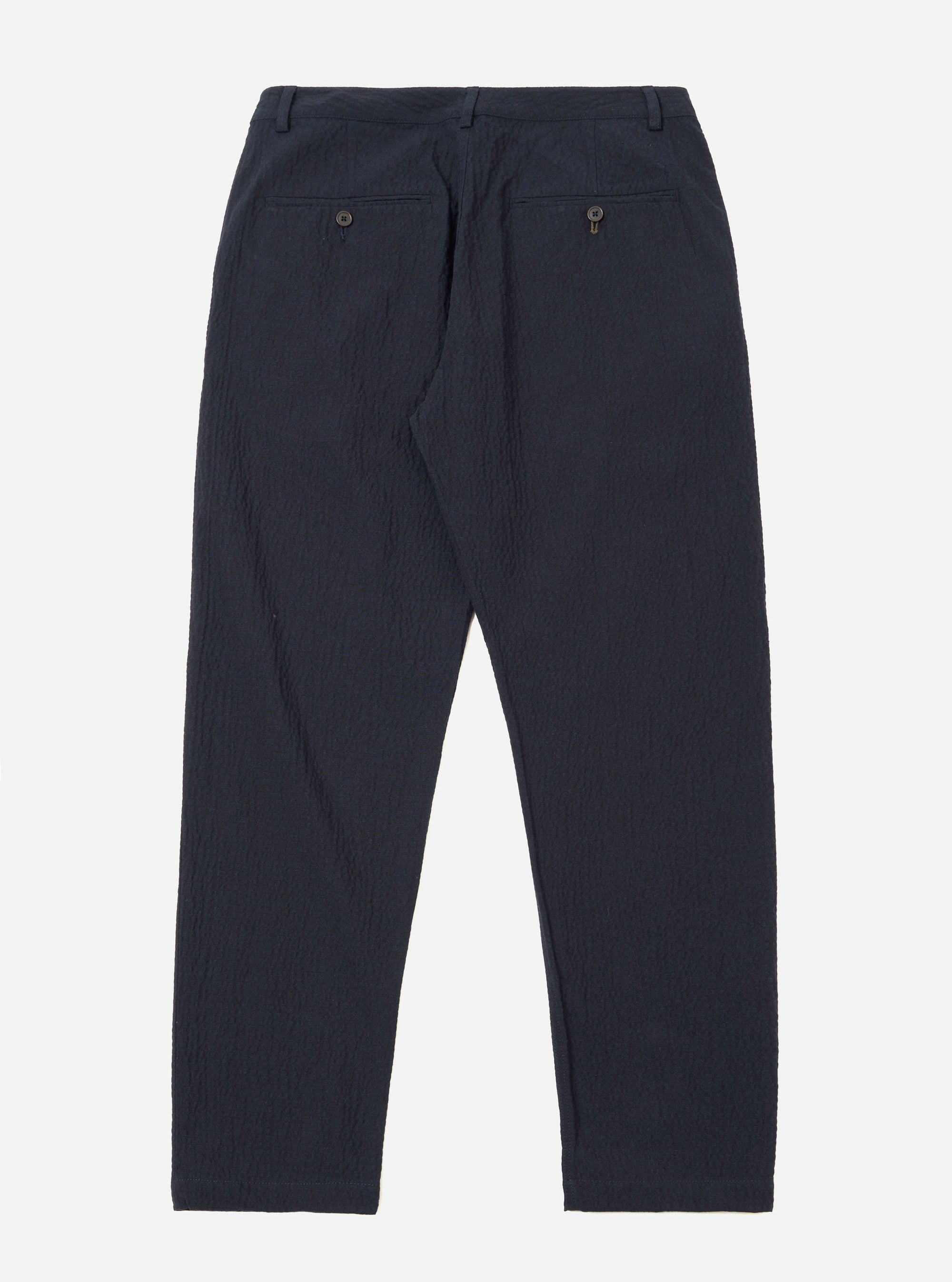 The Dark Navy Ospina Cotton Military Chino is shown from a rear angle as a flat lay against a plain white background. The image highlights the two rear patch pockets, one with a button-down flap, and the structured waistband with belt loops. The dark navy fabric features a visible puckered seersucker texture.