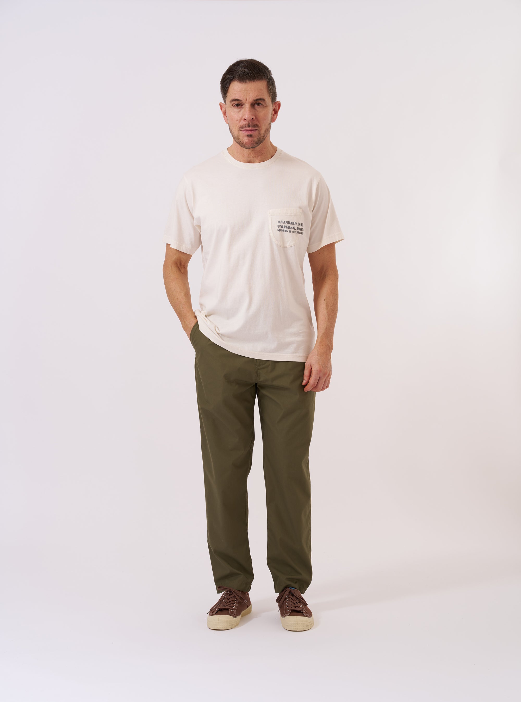 The Olive Recycled Polytech Military Chino is presented as a flat lay against a plain white background. The trousers feature a button fly, belt loops, and two slanted front pockets. The olive green fabric appears smooth with a technical finish.