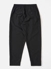 The Black Tropical Suiting Pleated Track Pant is shown from the back as a flat lay against a plain white background. The image highlights the clean construction of the trousers, featuring two rear pockets: one buttoned flap pocket on the left and one button jetted pocket on the right. The black tropical suiting fabric appears smooth and lightweight.
