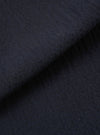 A close-up fabric swatch of the Dark Navy Ospina Cotton Oxford Pant highlights the deep navy blue color and the distinct puckered texture of the seersucker fabric. The material fills the frame, providing a detailed view of the garment's weave and finish.