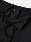 The Black Recycled Polytech Pleated Track Pant is shown from a rear three-quarter angle as a flat lay against a plain white background. The image highlights the tapered leg, a rear patch pocket with a buttoned flap, and the smooth, technical texture of the black recycled polytech fabric.