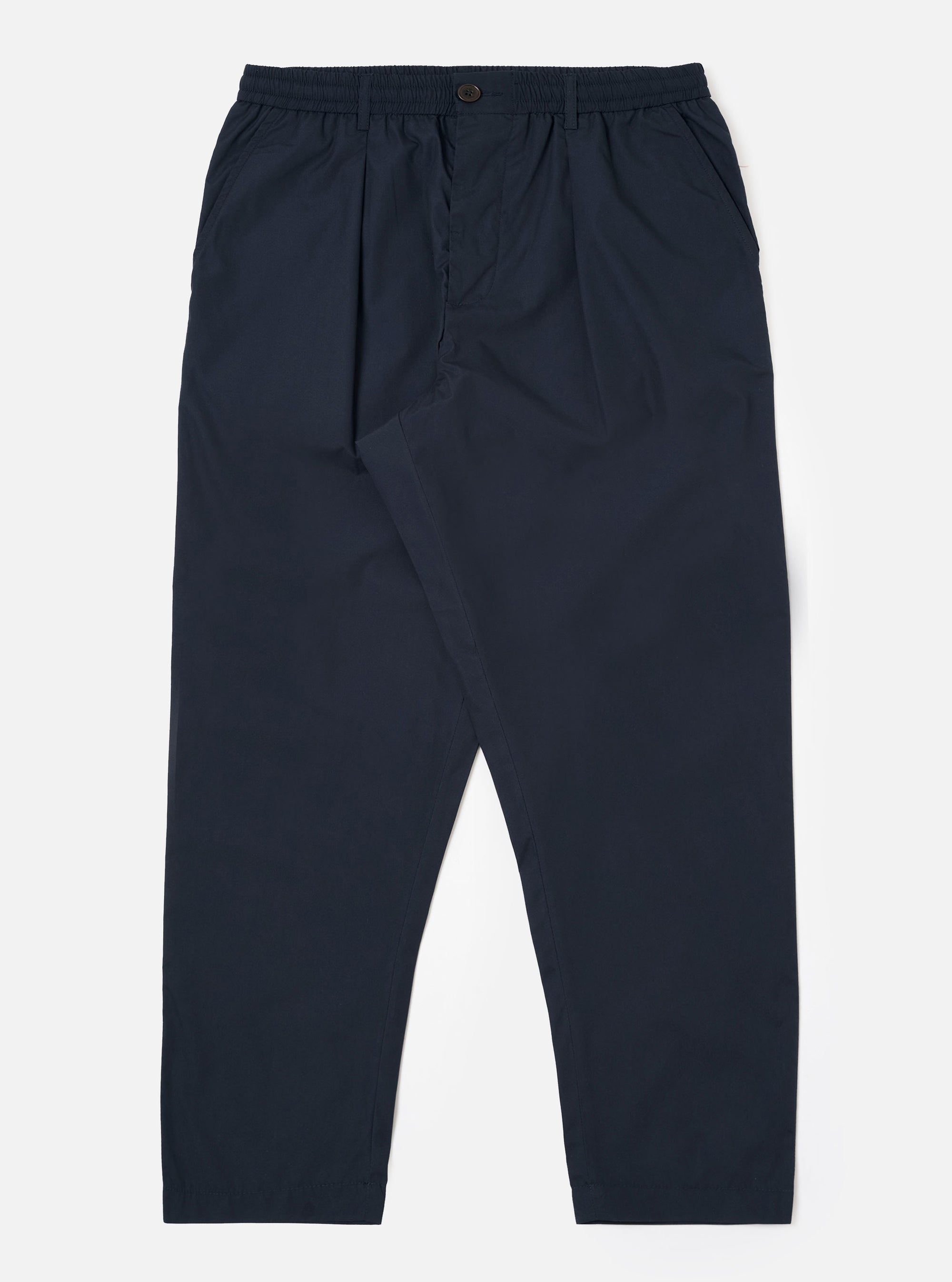 The Navy Recycled Polytech Pleated Track Pant is displayed as a flat lay against a plain white background. The trousers feature a loose, tapered fit with a single pleat at the front, an elasticated waistband with a tonal drawstring, and two side pockets. The dark navy recycled polytech fabric has a smooth, clean finish.