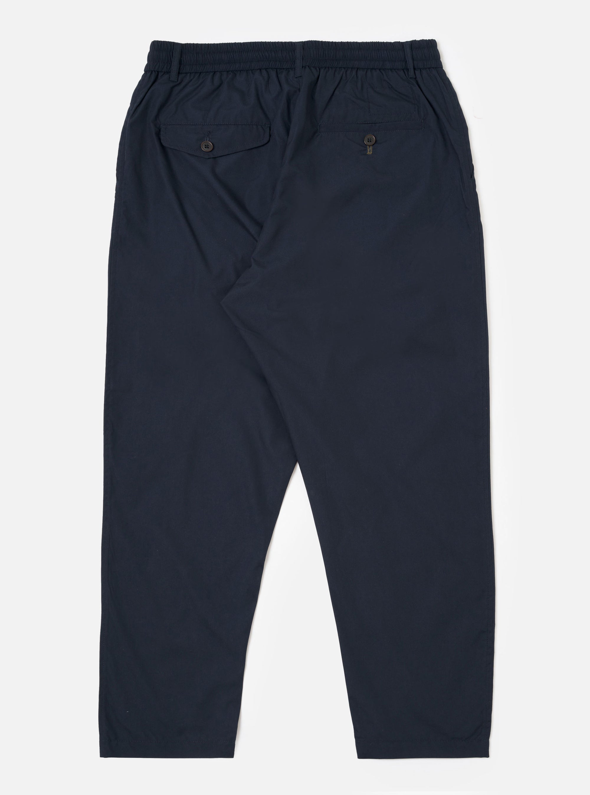 The Navy Recycled Polytech Pleated Track Pant is shown from the back as a flat lay against a plain white background. The image highlights the elasticated waistband and the two rear pockets, featuring one button-down flap pocket and one jetted pocket. The dark navy fabric appears smooth with a technical, utilitarian finish.