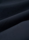 The Navy Recycled Polytech Pleated Track Pant is shown from a rear angle as a flat lay against a plain white background. The image highlights the elasticated waistband and two rear pockets, including one with a buttoned flap and one jetted pocket. The dark navy fabric appears smooth with a technical finish.
