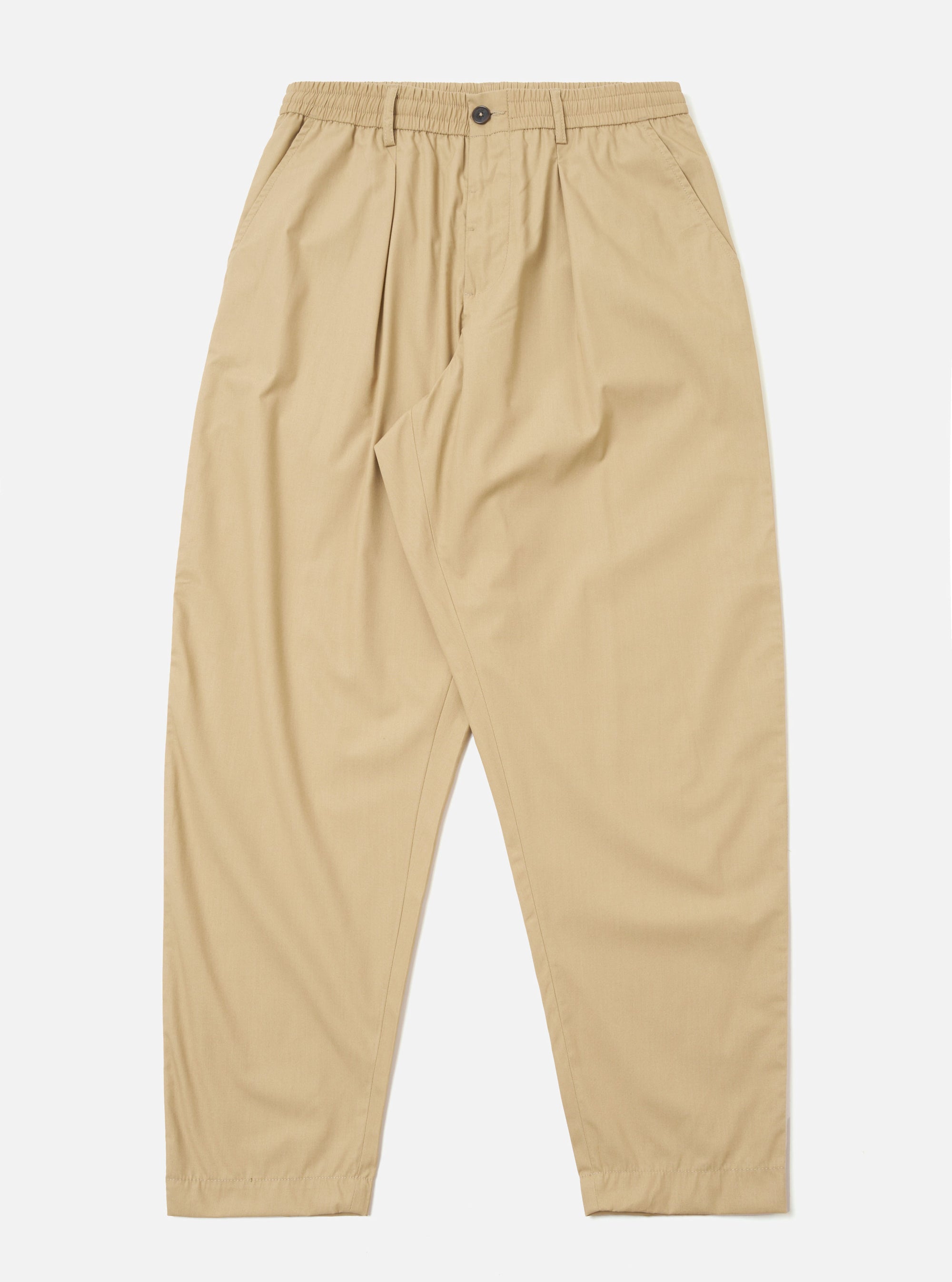 The Sand Recycled Polytech Pleated Track Pant is displayed as a flat lay against a plain white background. The trousers feature an elasticated waistband with an internal drawstring, a single pleat at the front of each leg, and a tapered silhouette. Two side pockets are visible. The fabric is a smooth, sand-colored recycled polytech material.