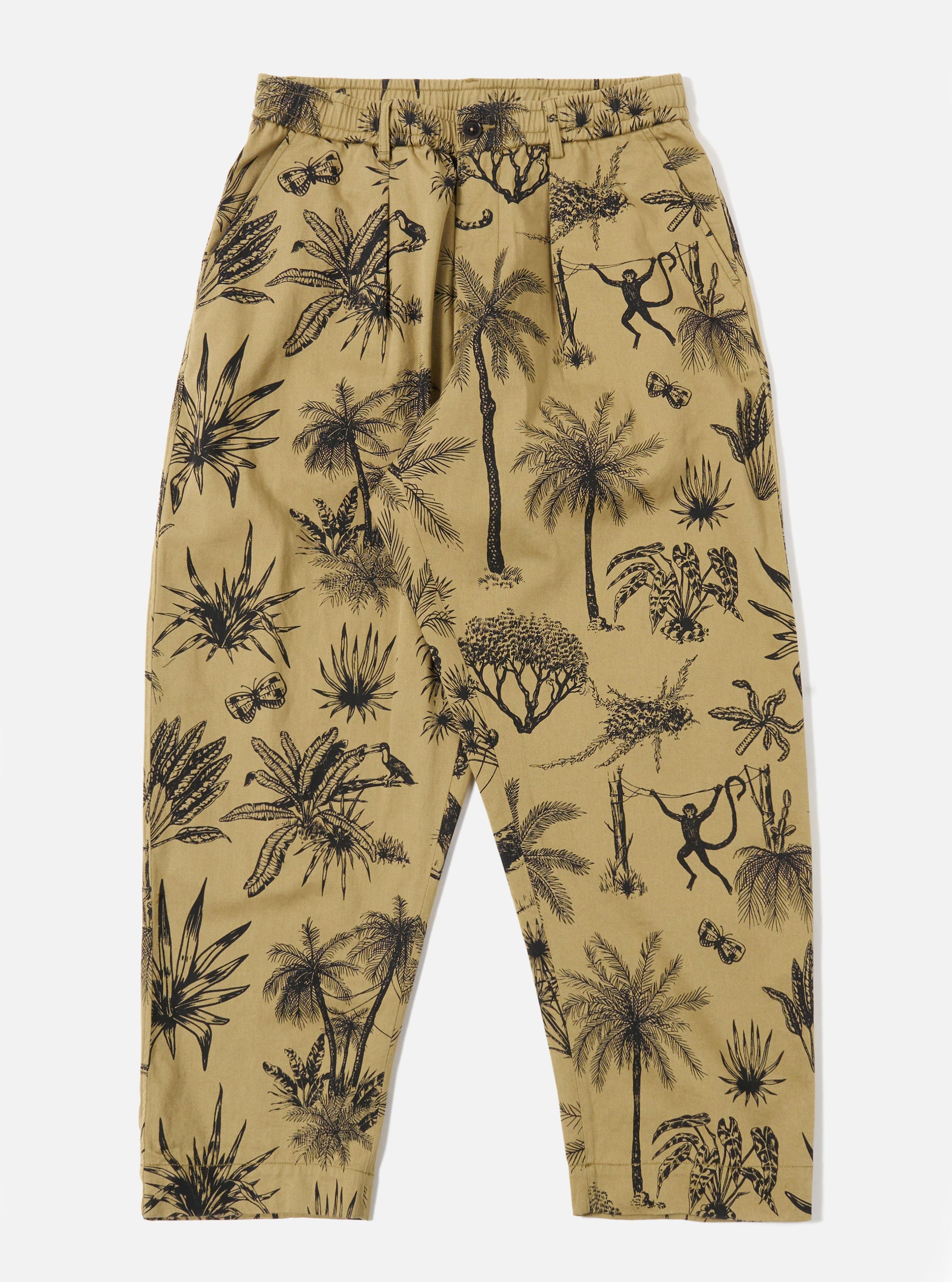 The Sand Jungle Toile Twill Oxford Pant is displayed as a flat lay against a plain white background. The trousers feature an all-over intricate jungle toile print in a dark shade over a sand-colored base. They are designed with a wide-leg silhouette, a pleated front, and an elasticated waistband with a drawstring.