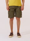 A model wears the Olive Recycled Polytech Parachute Short while standing against a plain white background. The shorts feature a relaxed, wide-leg fit, an elasticated waistband with an integrated drawstring, and large side pockets. The garment is made from a smooth, olive green technical fabric. The model is shown from the waist down, providing a clear view of the front and side profile of the shorts.