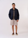 The Brown Kennedy Stripe Pleated Track Short is shown as a flat lay against a plain white background. The shorts feature a vertical striped pattern in shades of brown and tan, with an elasticated waistband and a visible single-pleat design on the front.