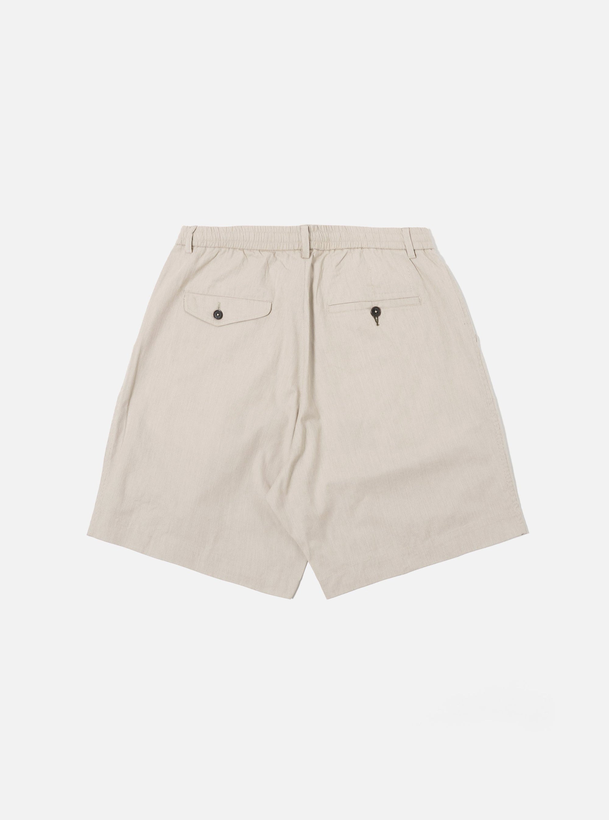 The Brown Kennedy Stripe Pleated Track Short is shown from the back as a flat lay against a plain white background. The image highlights the rear construction, featuring one button-down flap pocket on the right side and a simple welt pocket on the left. The fabric displays a brown and cream vertical stripe pattern throughout.