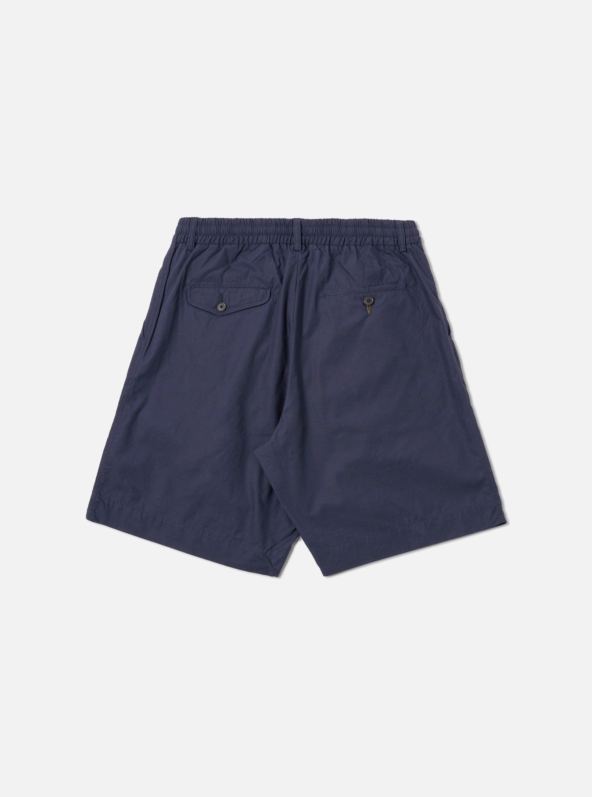 The Navy Peached Poplin Pleated Track Short is shown from the back as a flat lay against a plain white background. The shorts feature an elasticated waistband and a single rear patch pocket on the right side. The navy blue cotton fabric has a smooth, soft peached finish.