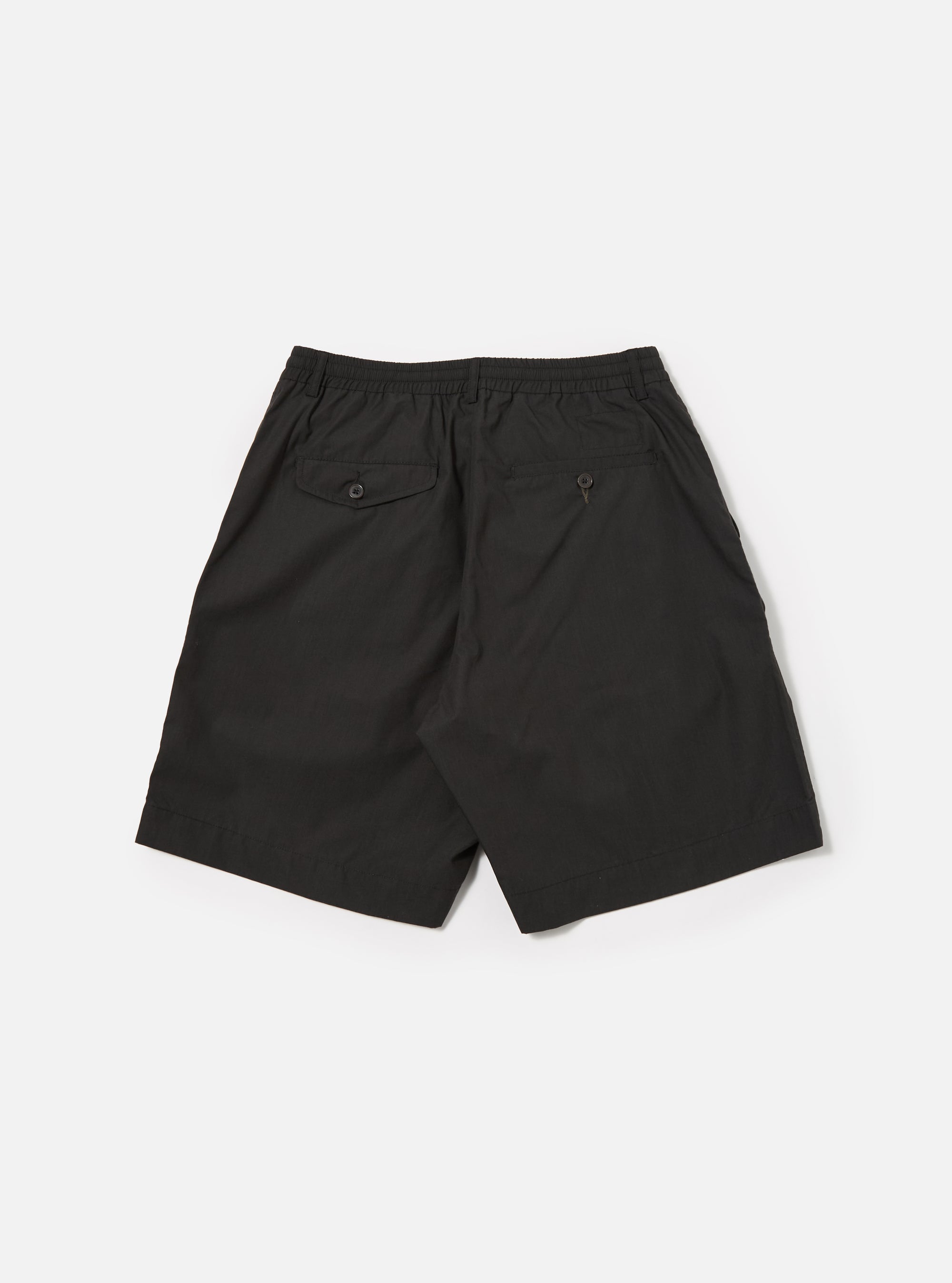 The Black Recycled Polytech Pleated Track Short is shown from the back as a flat lay against a plain white background. The image highlights the elasticated waistband and the two rear patch pockets. The smooth, black recycled polytech fabric features visible tonal stitching.