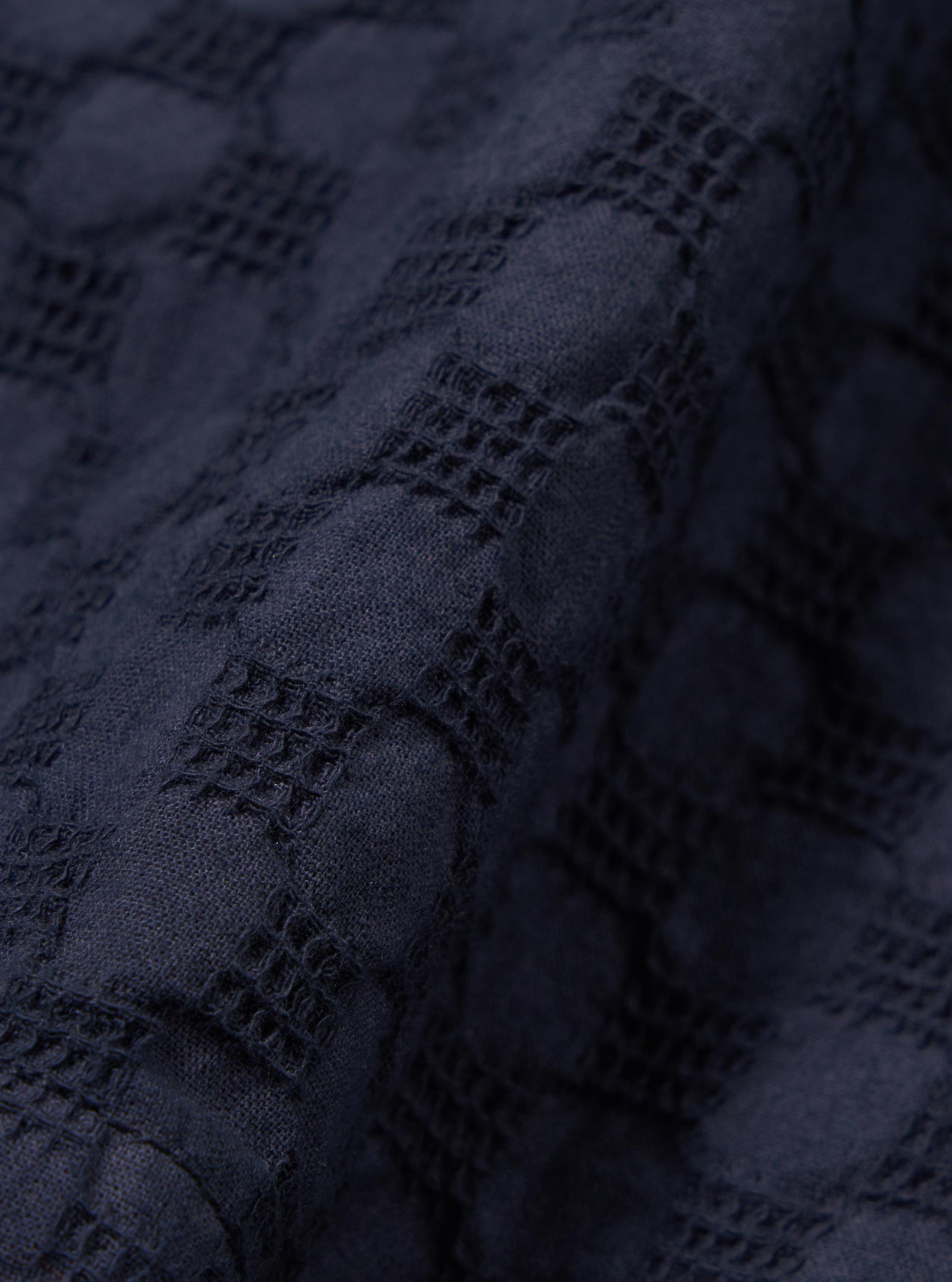 A close-up swatch image of the Navy Dot Waffle Simple Short fabric highlights a deep navy blue color with a distinct waffle knit texture. The fabric features a pattern of small, raised circular dots evenly spaced across the textured surface.