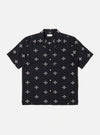 The Black Embroidered Diamond Camp Shirt is shown as a flat lay against a white background. The shirt features a camp collar, short sleeves, a full button-down front with tonal buttons, and a single chest pocket on the left side. A subtle, repeating diamond pattern is embroidered throughout the black fabric.