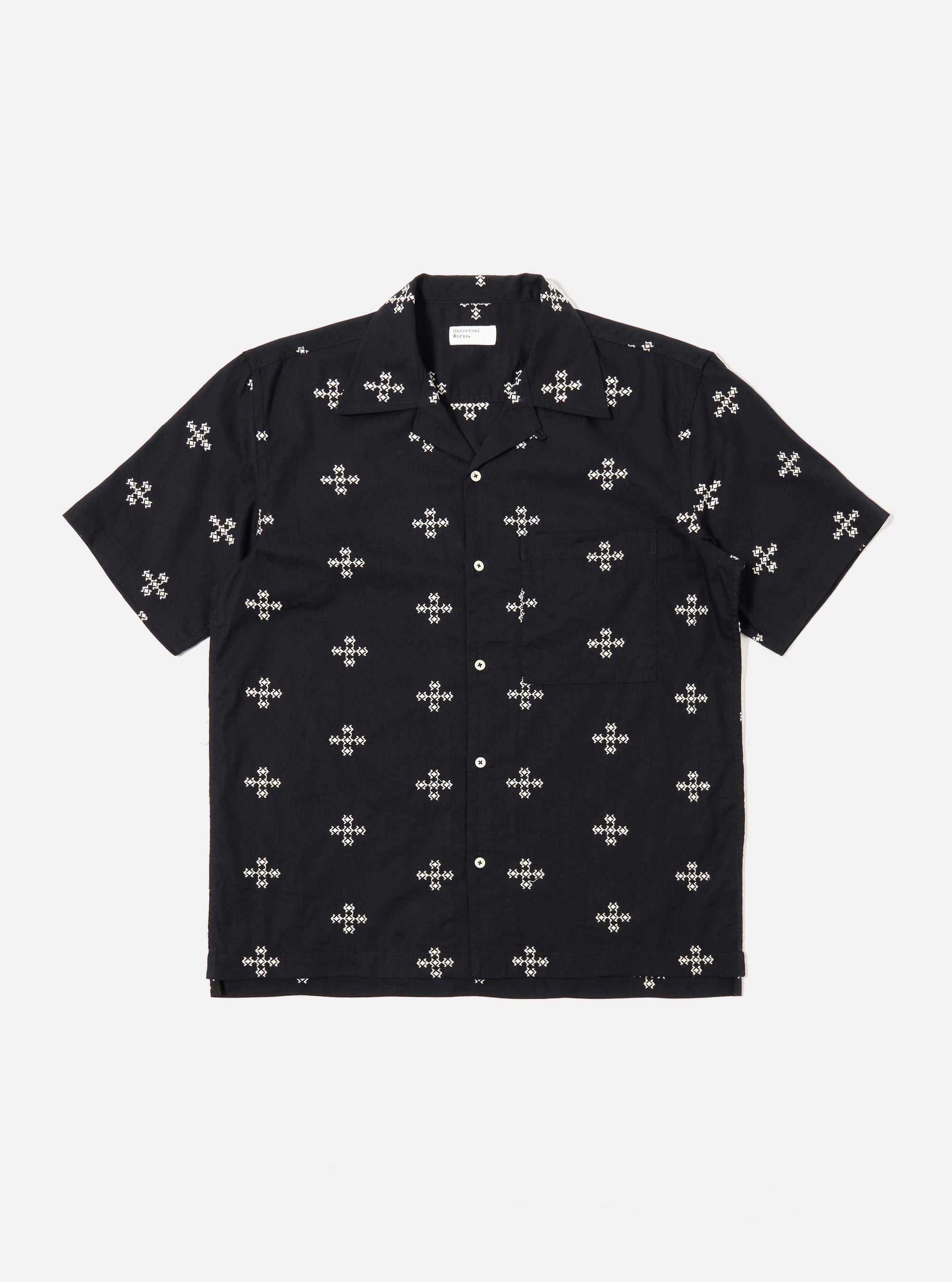 The Black Embroidered Diamond Camp Shirt is shown as a flat lay against a white background. The shirt features a camp collar, short sleeves, a full button-down front with tonal buttons, and a single chest pocket on the left side. A subtle, repeating diamond pattern is embroidered throughout the black fabric.