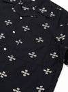 The Black Embroidered Diamond Camp Shirt is shown from a rear angle as a flat lay against a plain white background. The image highlights the back of the shirt, showcasing the straight hem, short sleeves, and the continued pattern of the embroidered diamond design across the shoulders and back panel.