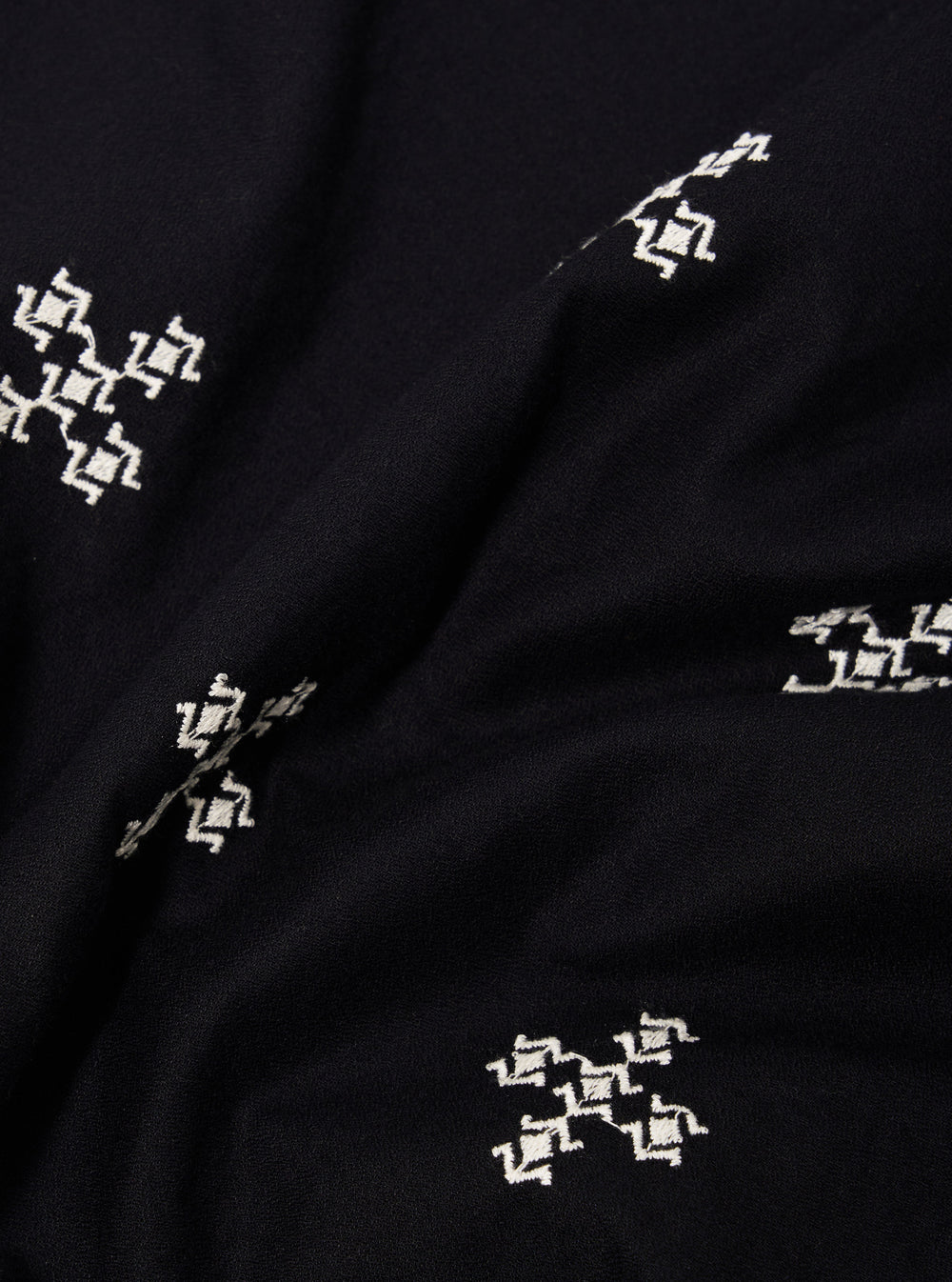 A close-up fabric swatch of the Black Embroidered Diamond Camp Shirt highlights the intricate diamond-patterned embroidery stitched in a slightly lighter thread against the black viscose fabric. The texture of the material and the detailed geometric pattern are the focal points of the image. No model or mannequin is present.