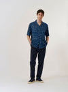 The Indigo Block Print Circles Camper Shirt is shown as a flat lay against a white background. The shirt features a camp collar, a full-length button-down front, and a single chest pocket. The indigo blue fabric is decorated with a repeating pattern of white block-printed circles.