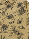 The Sand Jungle Toile Twill Windcheater Jacket is shown from a rear angle as a flat lay against a plain white background. The image highlights the all-over jungle toile print, featuring dark botanical and animal illustrations on a sand-colored base. The jacket has a straight hem and a simple back construction with visible stitching.
