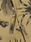 The Sand Jungle Toile Twill Windcheater Jacket is shown in a detail view as a flat lay against a plain white background. The image focuses on the lower half of the jacket, highlighting the intricate dark jungle toile print on the sand-colored twill fabric and the clean finish of the straight hem.