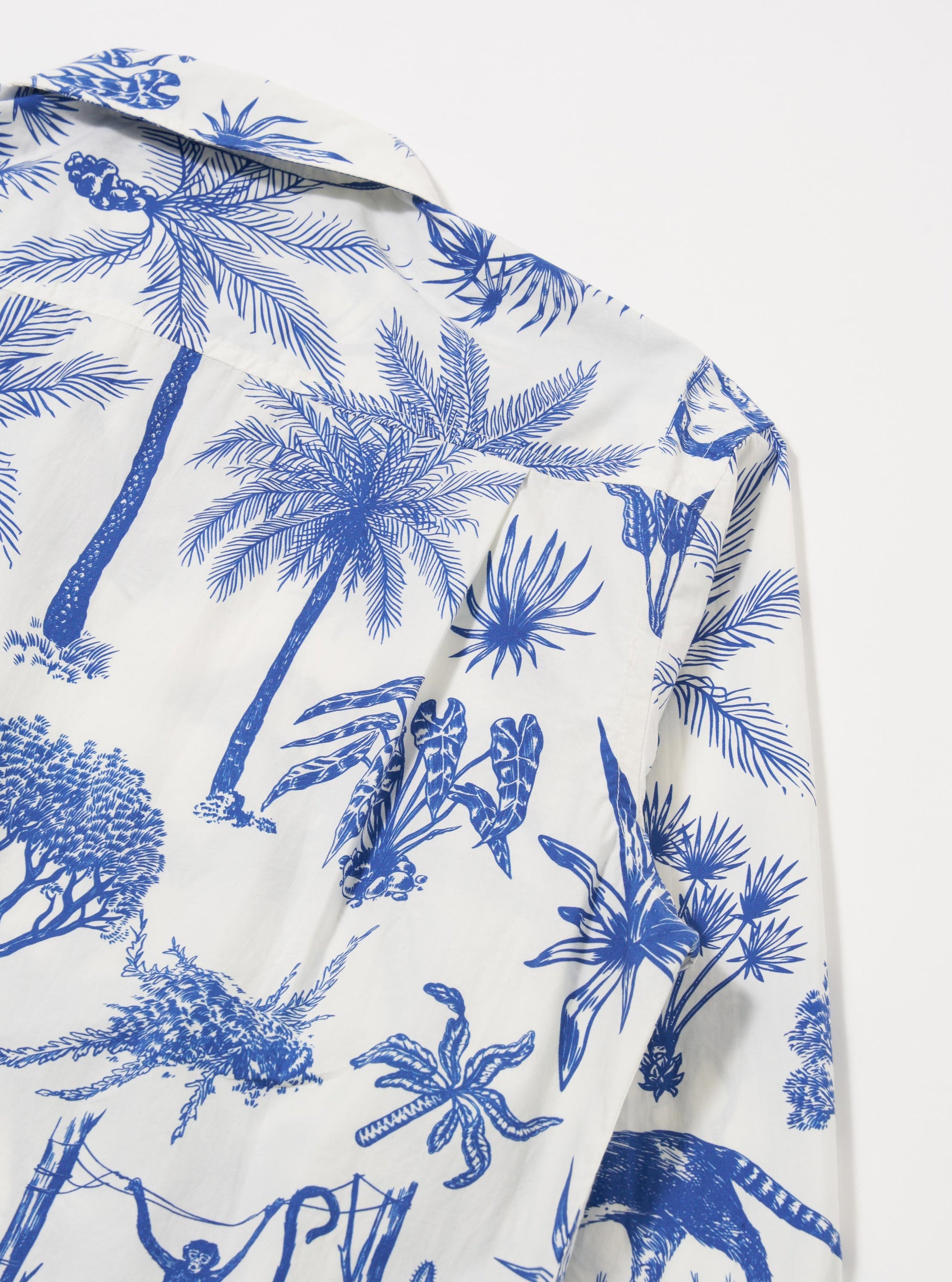 The White Jungle Toile Poplin Fatigue Shirt is shown from the back as a flat lay against a plain white background. The image highlights the shirt's straight-cut hem and the detailed jungle toile print, which features dark illustrations of wildlife and tropical flora on a white base.