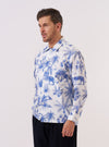 A model wears the White Jungle Toile Poplin Fatigue Shirt over a dark-colored shirt against a plain white background. The shirt features an all-over jungle toile print with green botanical and animal illustrations. It is designed with a one-piece flat collar, a single large square patch pocket on the chest, and large front buttons. The model is shown from the chest up in a medium shot.