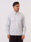 The Sky Urban Stripe Lazy Day Shirt is worn by a model standing against a plain white background. The shirt features a light blue and white vertical stripe pattern, a button-down collar, and a single asymmetrical chest pocket. The model is wearing the shirt buttoned up, showcasing its relaxed fit.