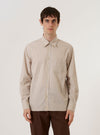 A model wears the Sand Urban Stripe Lazy Day Shirt while standing against a plain white background. The shirt features a vertical striped pattern in sand and white, a button-down front, and a single chest pocket. The model is wearing the shirt untucked over a light-colored undershirt.
