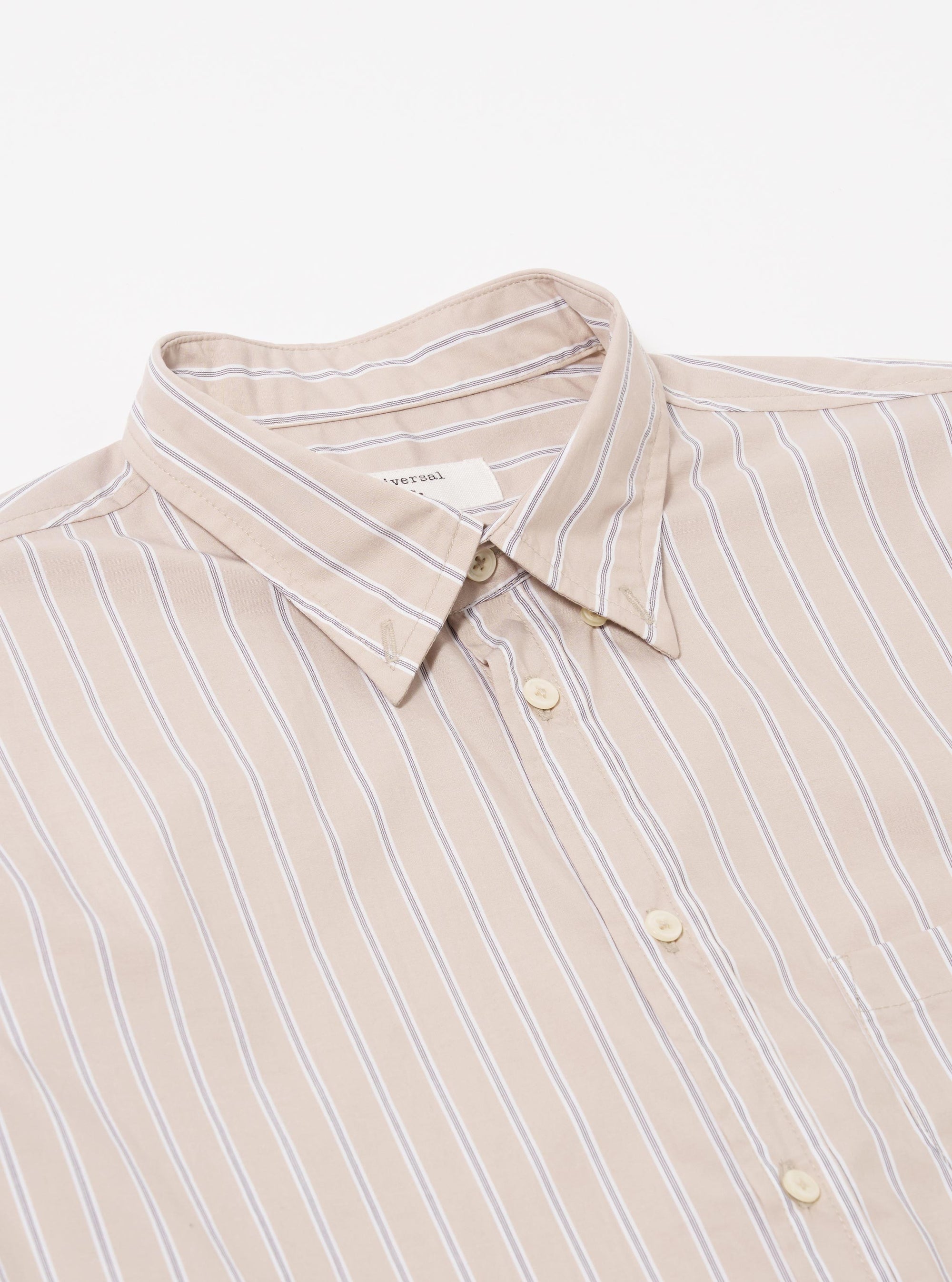 The Sand Urban Stripe Lazy Day Shirt is shown from the back as a flat lay against a plain white background. This view highlights the shirt's back yoke and a central box pleat, emphasizing its relaxed fit. The cotton fabric features a vertical stripe pattern in sand and stone colors.