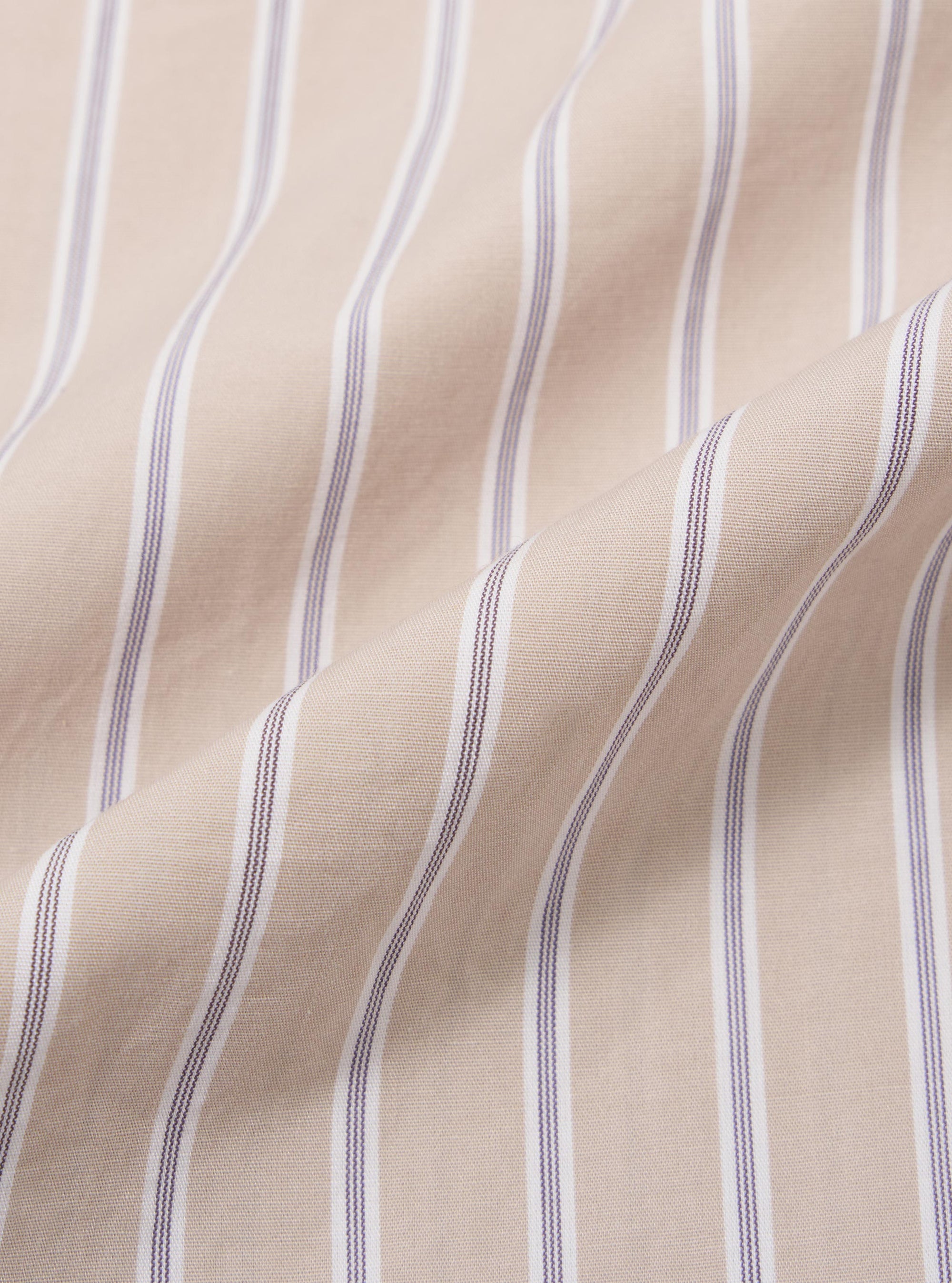 A close-up fabric swatch of the Sand Urban Stripe Lazy Day Shirt displays a pattern of vertical sand-colored and white stripes. The image focuses on the fine texture and weave of the cotton material. No model or mannequin is present.