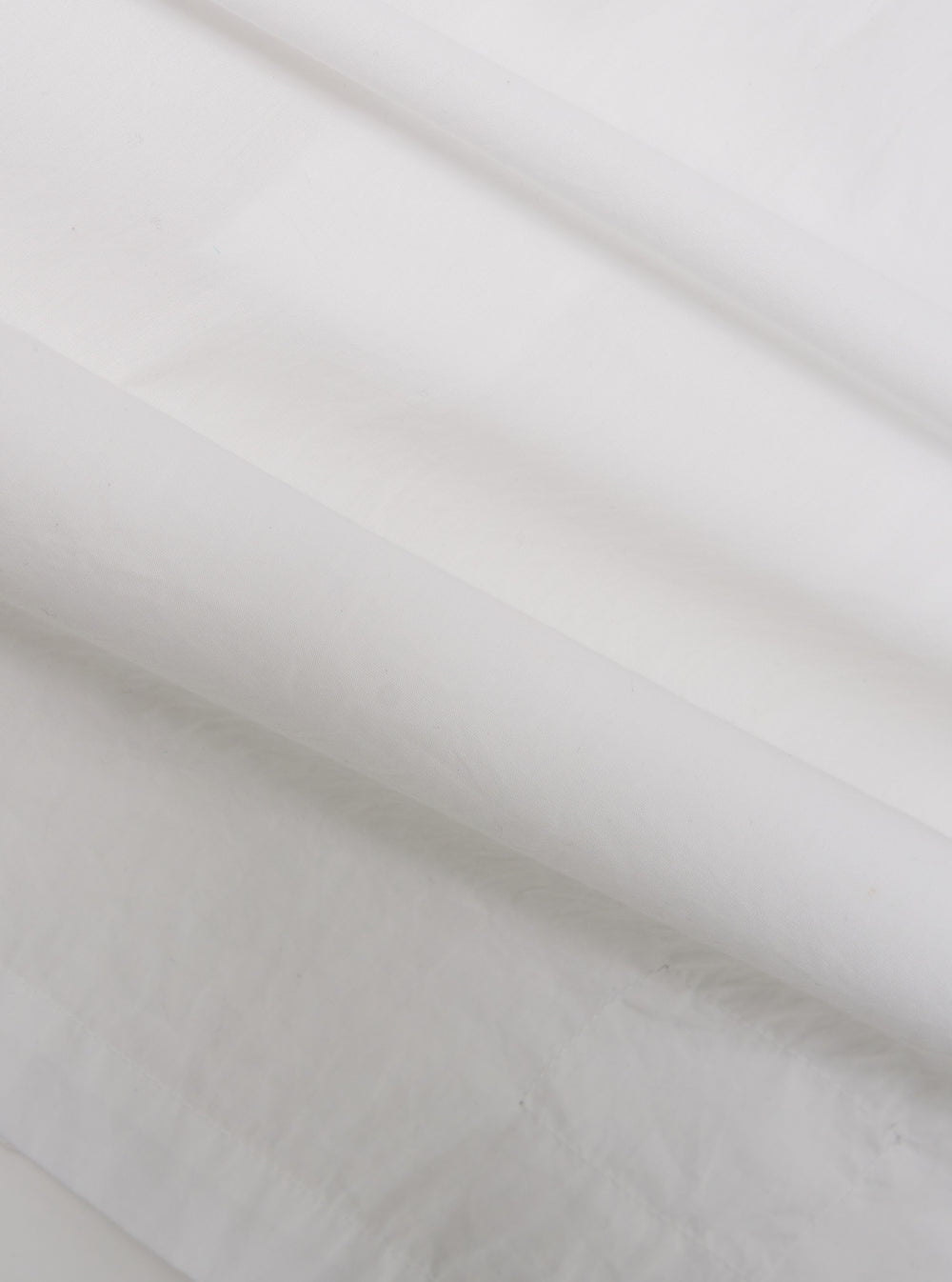 A close-up swatch of the White Poplin Dwight Overshirt highlights the smooth and tightly woven texture of the white cotton poplin fabric. The material fills the frame, providing a detailed view of the garment's clean, crisp finish and solid white color.