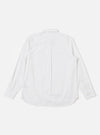 A model wears the White Poplin Patched Lazy Day Shirt against a neutral studio background. The shirt is styled open over a white t-shirt, showcasing its relaxed silhouette, simple collar, and tonal patchwork details. A single asymmetric chest pocket is prominent on the left side of the garment.