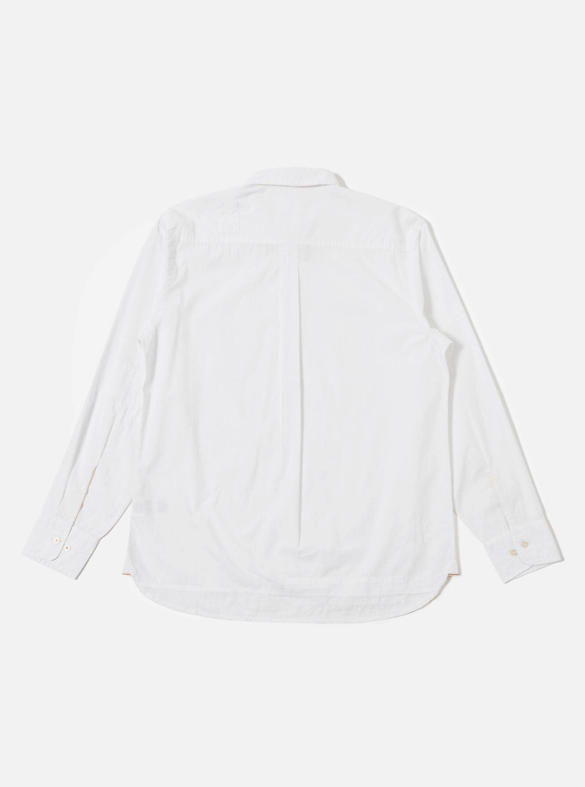 A model wears the White Poplin Patched Lazy Day Shirt against a neutral studio background. The shirt is styled open over a white t-shirt, showcasing its relaxed silhouette, simple collar, and tonal patchwork details. A single asymmetric chest pocket is prominent on the left side of the garment.