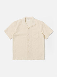 The Ecru Dot Waffle Road Shirt is shown as a flat lay against a white background. The short-sleeve shirt features a camp collar with a loop closure, a central button-down front, and a single patch pocket on the left chest. The ecru-colored cotton fabric has a distinct dot waffle texture and a straight hem.