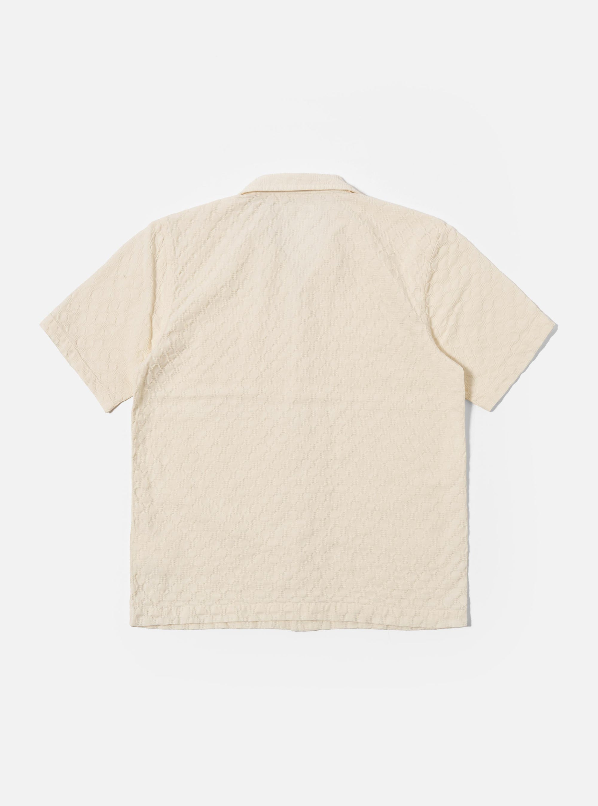 The Ecru Dot Waffle Road Shirt is shown from the back as a flat lay against a plain white background. The image highlights the shirt's straight hem, short sleeves, and the unique textured dot waffle cotton fabric in an ecru shade.