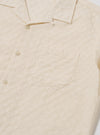 The Ecru Dot Waffle Road Shirt is shown from the back as a flat lay against a plain white background. The image highlights the shirt's straight hem, short sleeves, and the unique textured dot waffle pattern of the ecru cotton fabric.