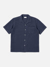 The Navy Dot Waffle Road Shirt is shown as a flat lay against a plain white background. The shirt features short sleeves, a camp collar with a loop closure at the neck, and a single chest patch pocket on the left side. The fabric has a distinct textured waffle pattern throughout.