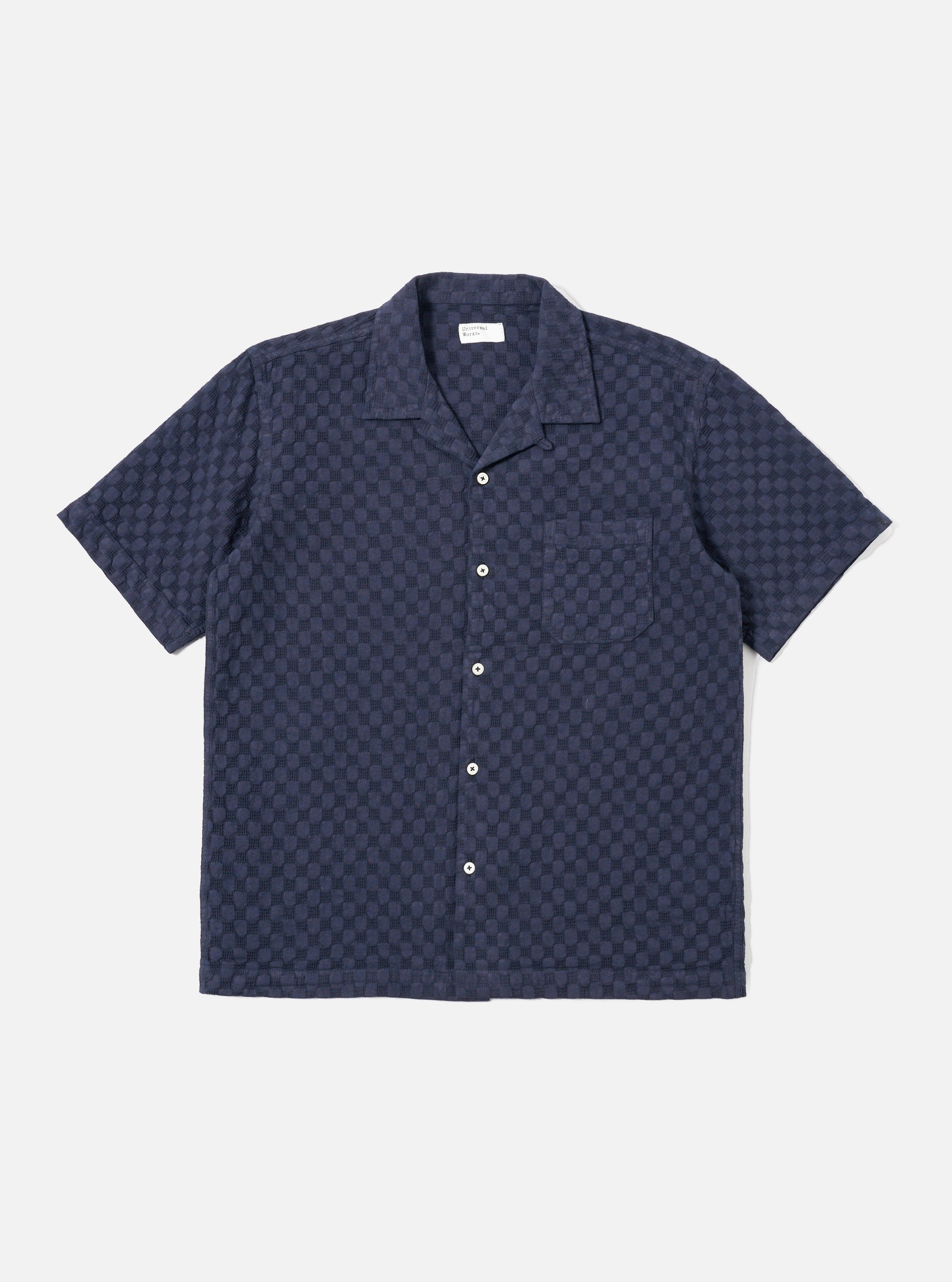 The Navy Dot Waffle Road Shirt is shown as a flat lay against a plain white background. The shirt features short sleeves, a camp collar with a loop closure at the neck, and a single chest patch pocket on the left side. The fabric has a distinct textured waffle pattern throughout.