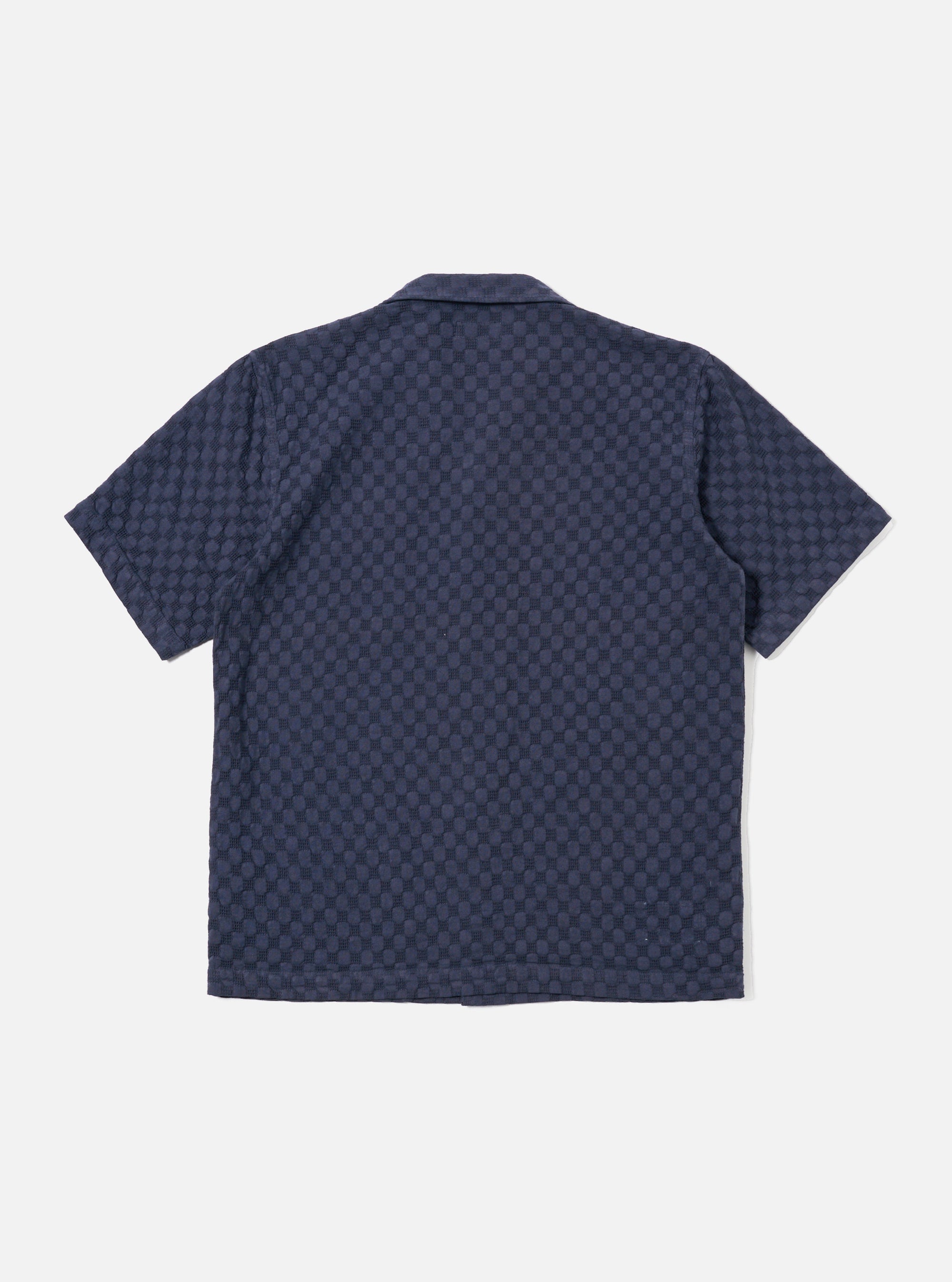 The Navy Dot Waffle Road Shirt is shown from the back as a flat lay against a plain white background. The shirt features a straight hem, short sleeves, and a structured one-piece collar. The fabric has a distinct rounded waffle texture throughout.