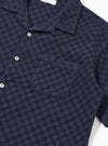 The Navy Dot Waffle Road Shirt is shown from a rear angle as a flat lay against a plain white background. The image highlights the shirt's straight hem, short sleeves, and the subtle textured dot waffle pattern of the navy blue cotton fabric.