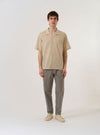 The Beige Fine Organic Cotton Sal Road Shirt is shown as a flat lay against a white background. The shirt features a relaxed camp collar, a central button-down front, and a single patch pocket on the left chest. The fabric is a smooth, fine organic cotton in a light beige shade.